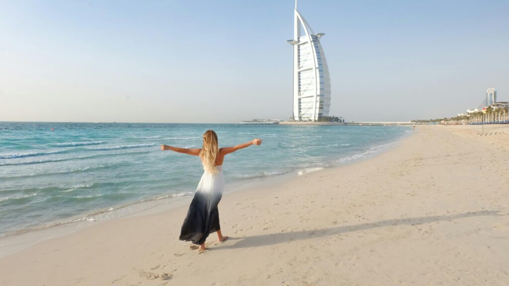 pexels-photo-1089645-1089645 A carefree woman in a flowing dress strolls along the Dubai beach with Burj Al Arab in view.