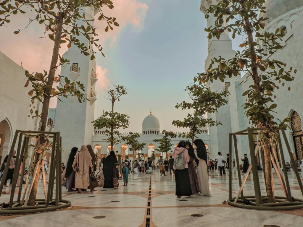 pexels-photo-17219208-17219208 A stunning view of the Sheikh Zayed Grand Mosque during sunset with people gathering under tree-lined pathways.