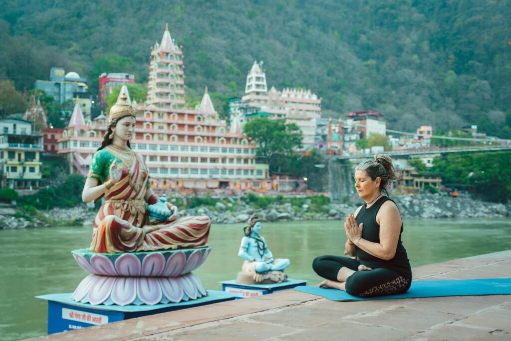 pexels-photo-20035462-20035462 Woman meditating beside a statue by the Ganges in Rishikesh, capturing spirituality and serenity.