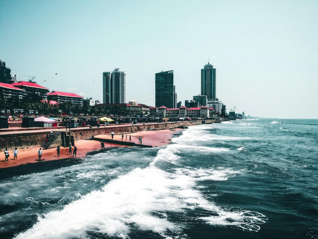 Scenic view of a coastal city with tall buildings and waves crashing against the shore.