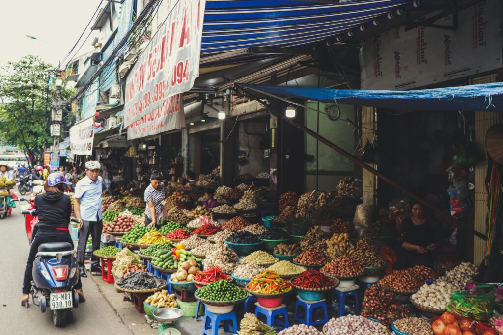 pexels-photo-2977435-2977435 Bustling outdoor street market in Hanoi featuring colorful produce and local vendors.
