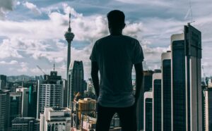 A silhouette of a man overlooking the Kuala Lumpur skyline, featuring the iconic KL Tower.