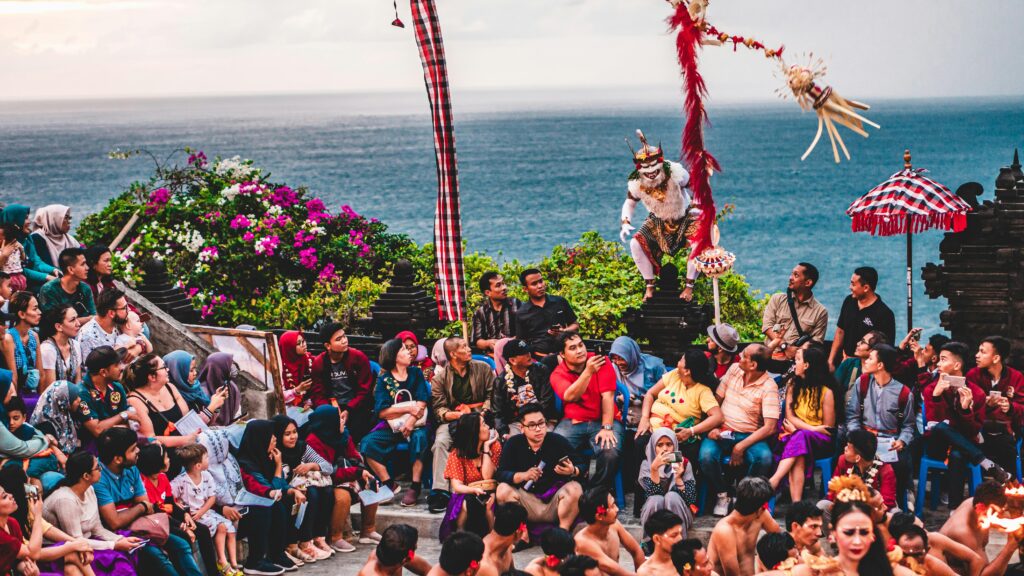 Colorful and lively traditional dance performance captivates a large outdoor audience by the sea.