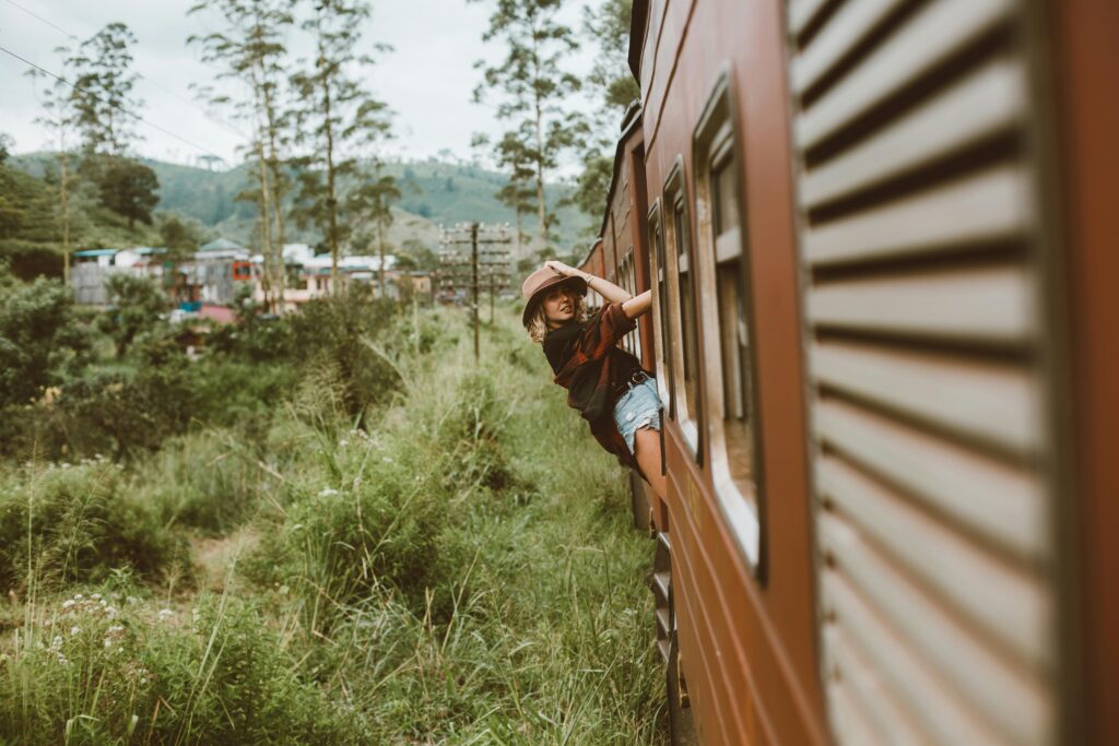pexels-photo-4553621-4553621 A young woman in casual attire enjoys a scenic train ride through lush countryside.