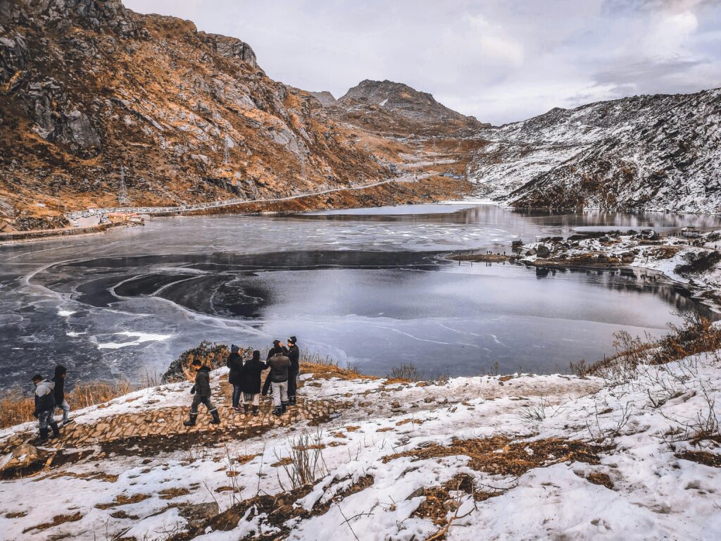 pexels-photo-5040253-5040253 A group of people admiring the scenic view of a frozen mountain lake during winter.