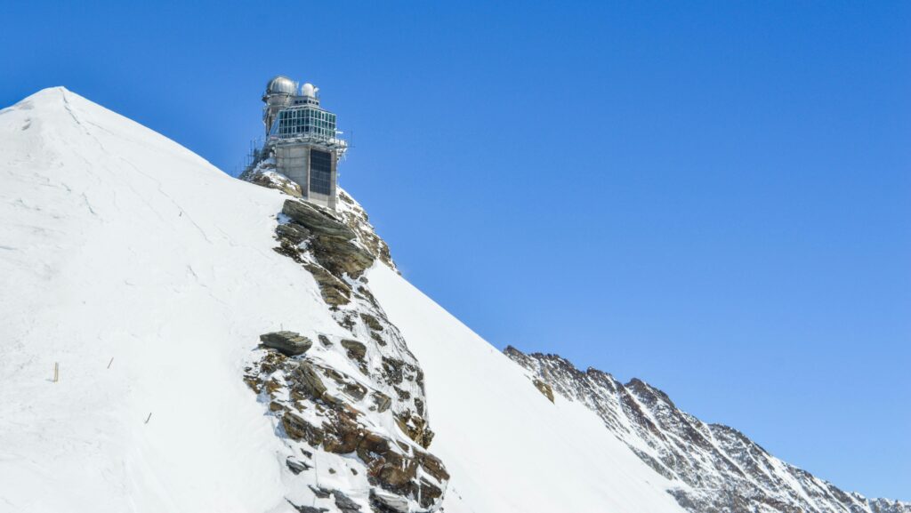 pexels-photo-5210435-5210435 Breathtaking view of an observatory perched on a snowy mountain under a clear blue sky.