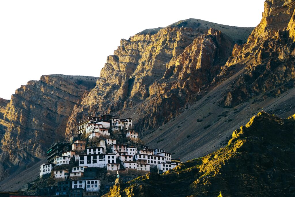 Stunning view of Key Monastery nestled in Spiti Valley, Himachal Pradesh, India against rocky mountain backdrop at sunset.
