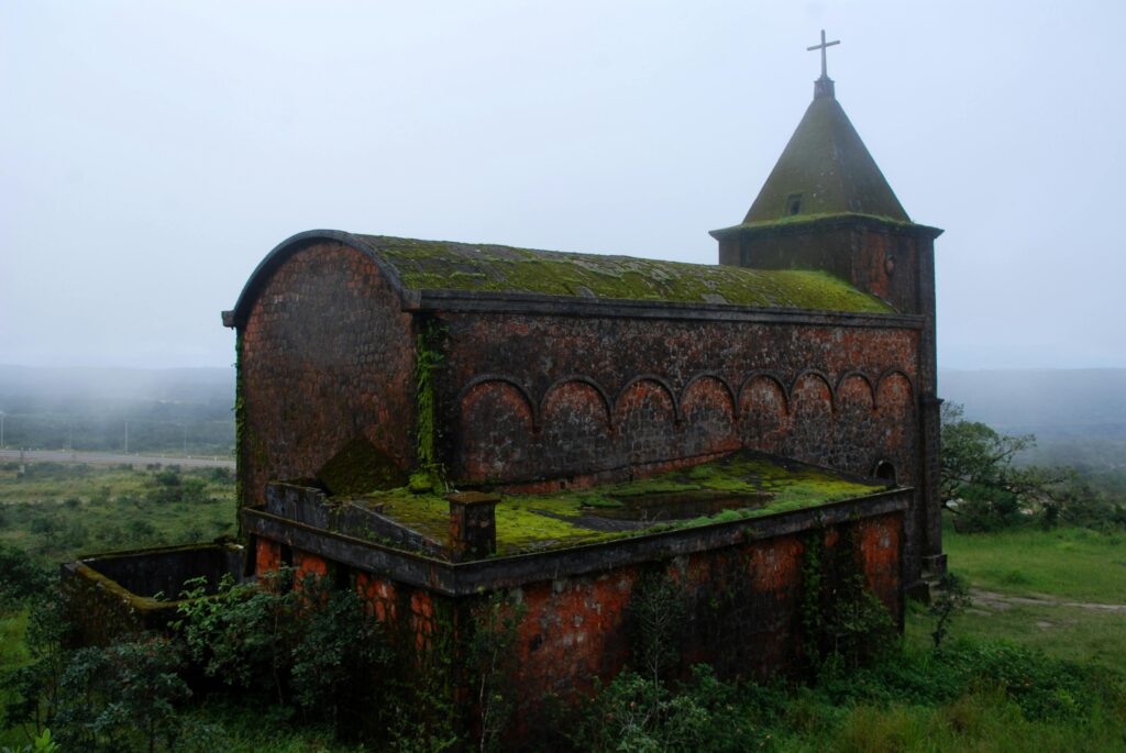 Historic moss-covered church in Bokor National Park, Cambodia, nestled in misty hills.