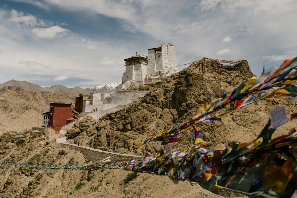 pexels-photo-6576294-6576294 Stunning view of Namgyal Tsemo Monastery in the Himalayas with prayer flags waving in the wind.