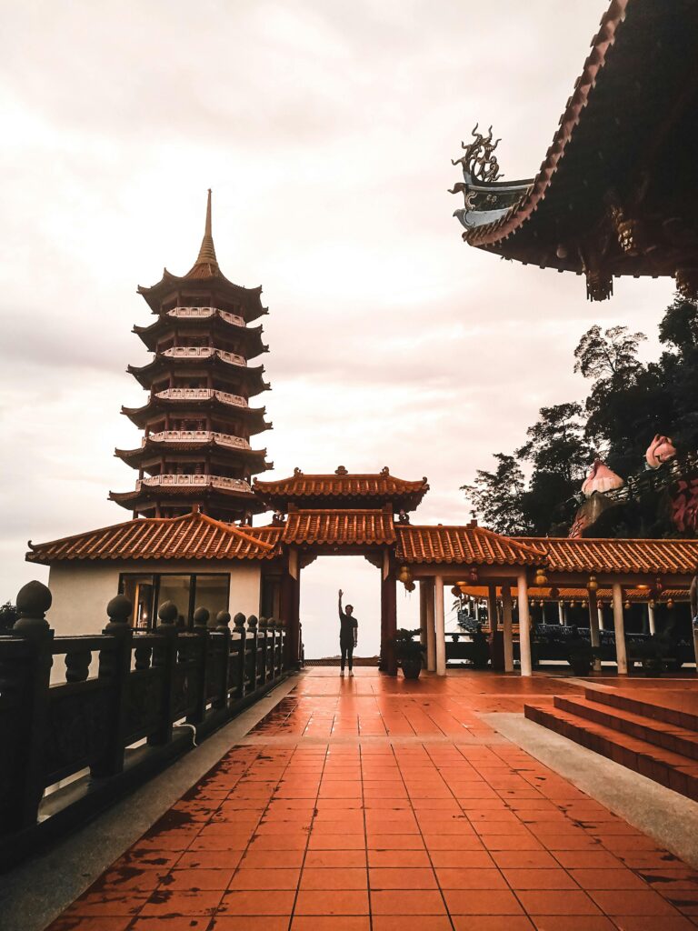Stunning view of Chin Swee Caves Temple's pagoda during sunset with a lone figure standing underneath.